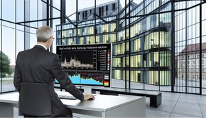 Europäischer Bankvorstand analysiert Immobilienportfolio-Daten an einem modernen Arbeitsplatz in einem deutschen Bürogebäude